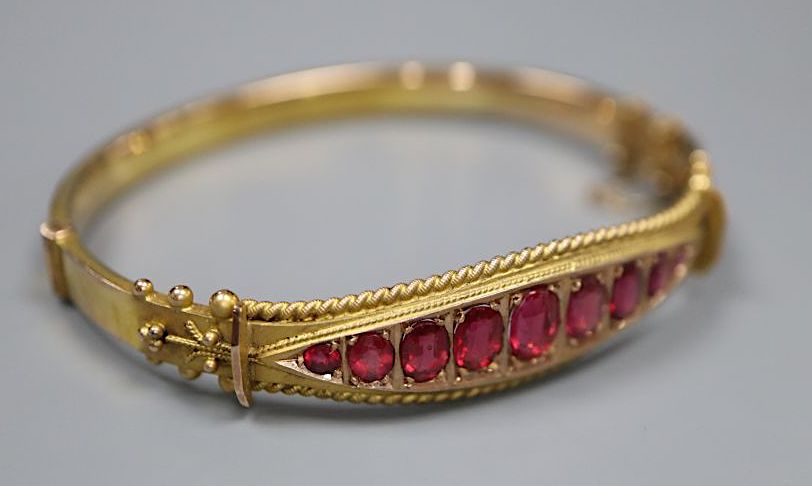 A cased Edwardian 9ct gold and graduated red stone doublet set hinged bracelet,